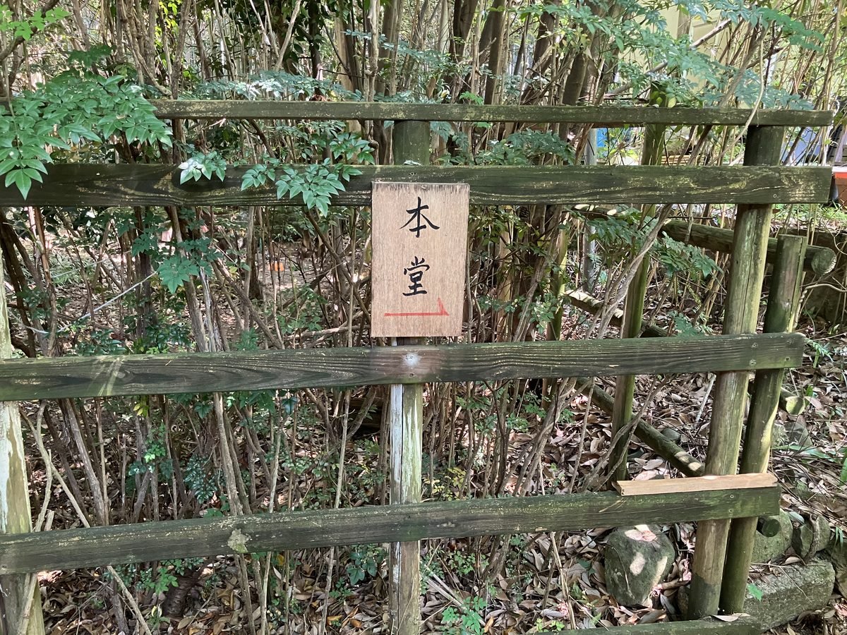 寫著「本堂」的木製指示牌，紅色箭頭指向右方