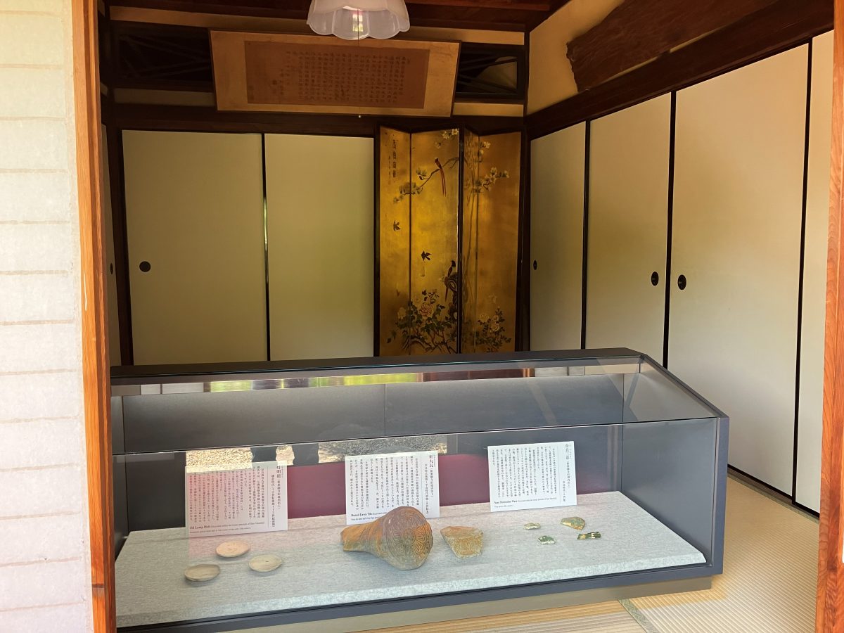 新薬師寺の展示ケース — 旧境内から出土した灯明皿・軒丸瓦・奈良三彩